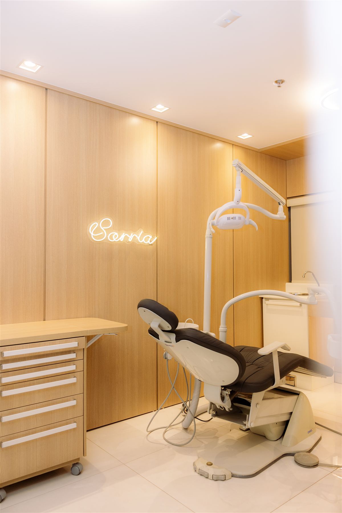 Consultório odontológico com cadeira reclinável e letreiro Sorria