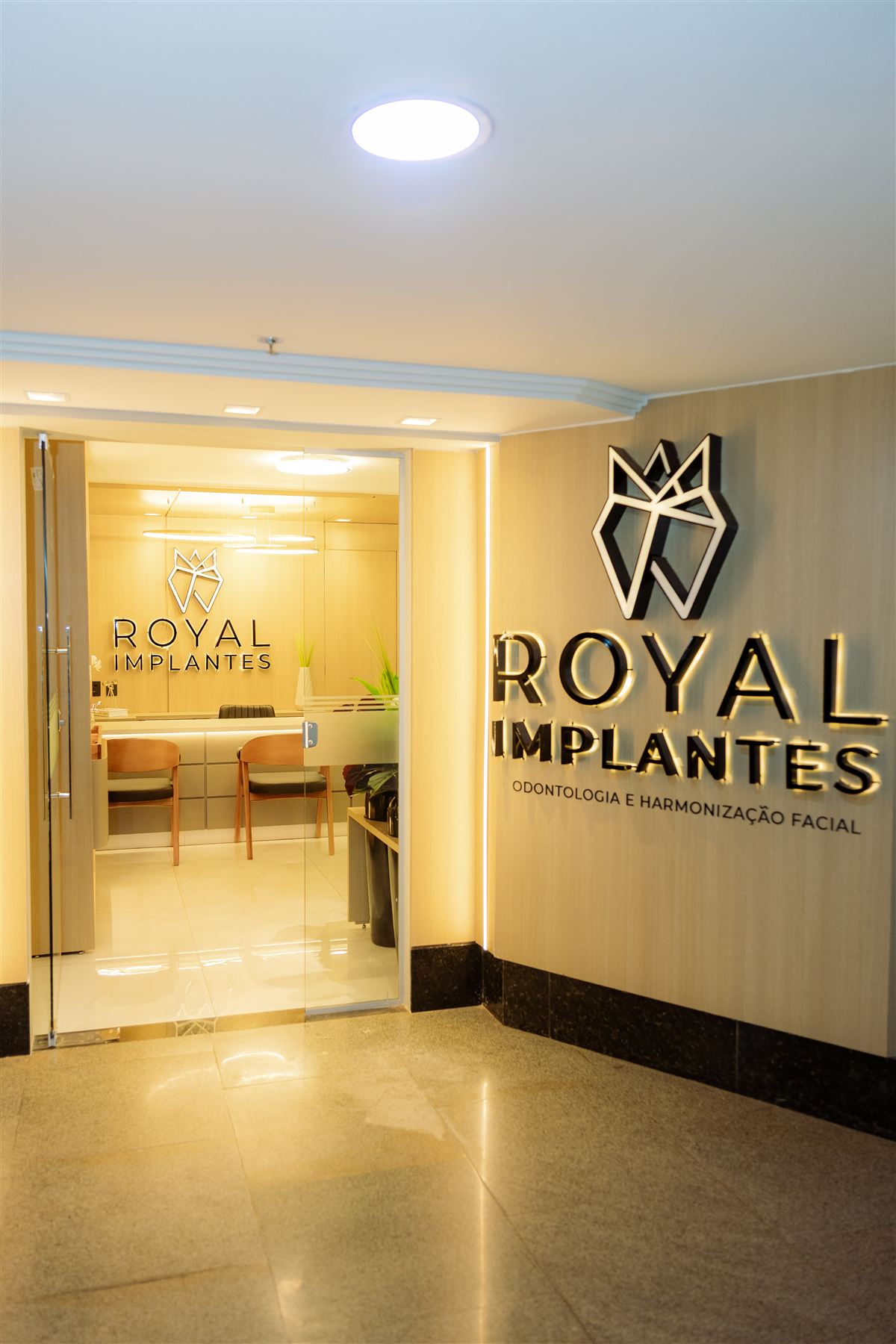 Entrada da clínica Royal Implantes com logo iluminado