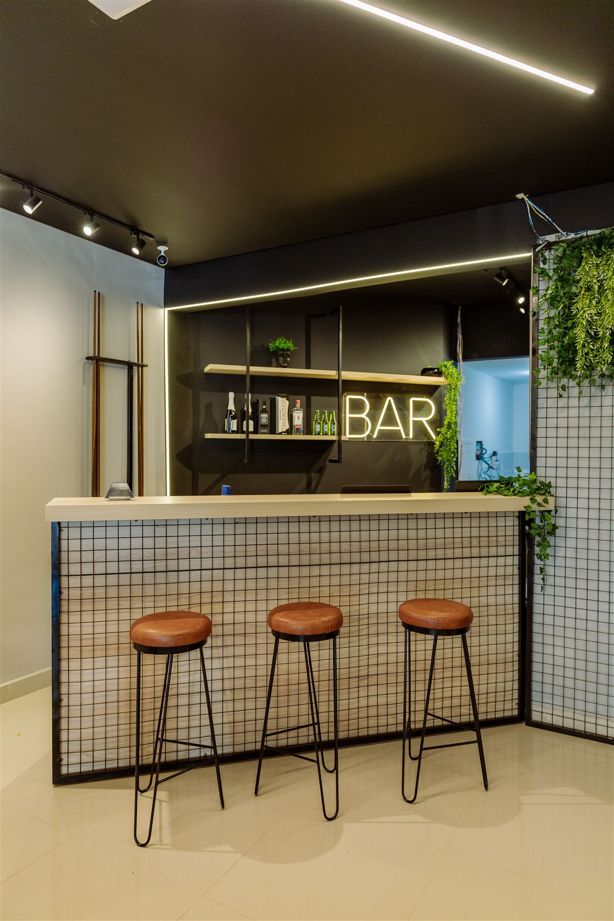 Bar interno da loja Elegance Outlet com letreiro luminoso e banquetas de couro