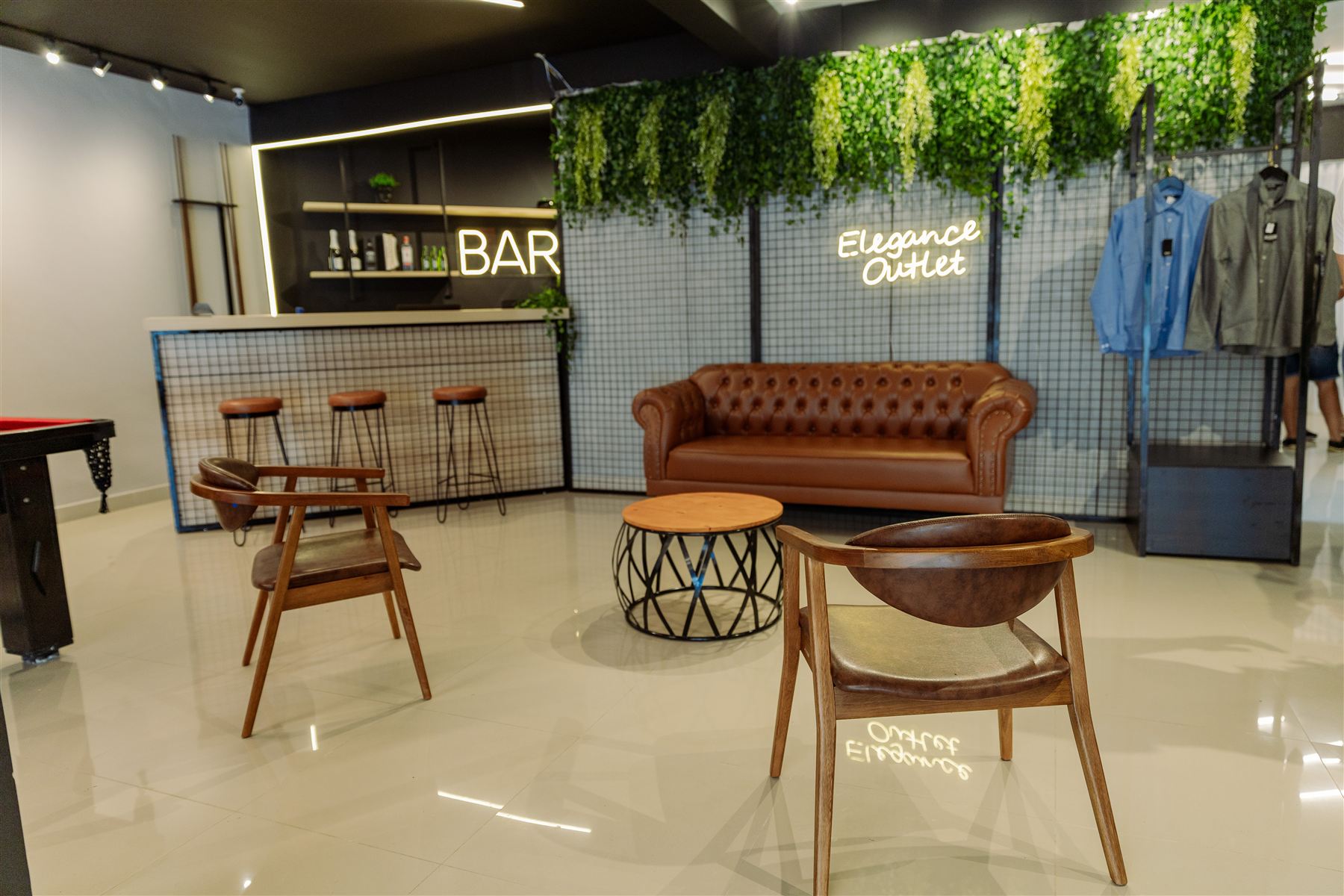 Lounge da loja Elegance Outlet com sofá de couro, poltronas e letreiro luminoso