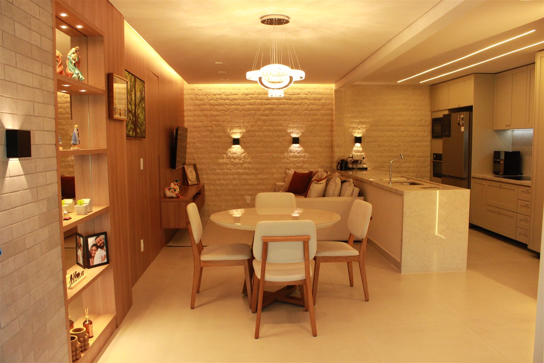 Sala de estar e jantar integradas com parede de pedra e iluminação projetada