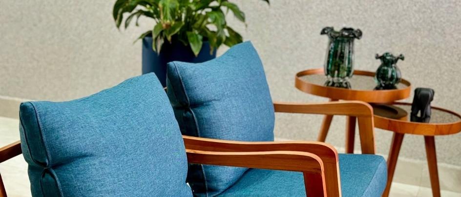 Poltronas azuis com estrutura em madeira e mesa lateral