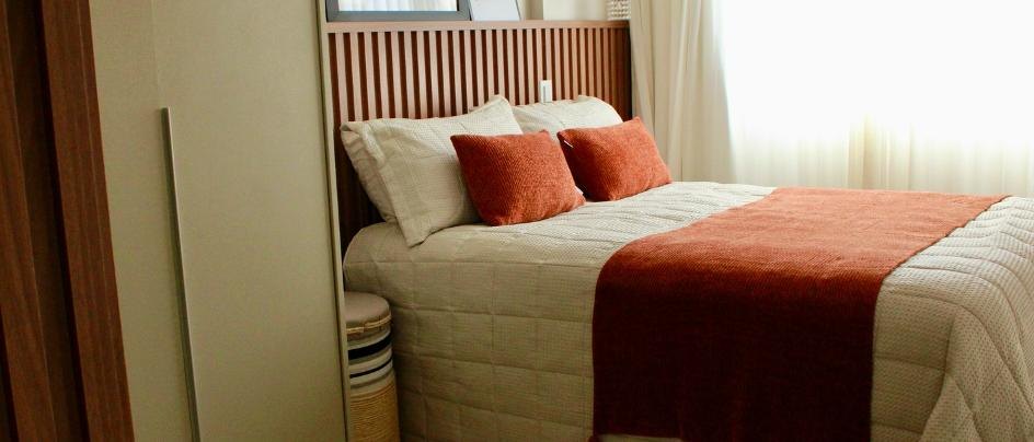 Quarto de casal com cabeceira ripada e roupa de cama em terracota