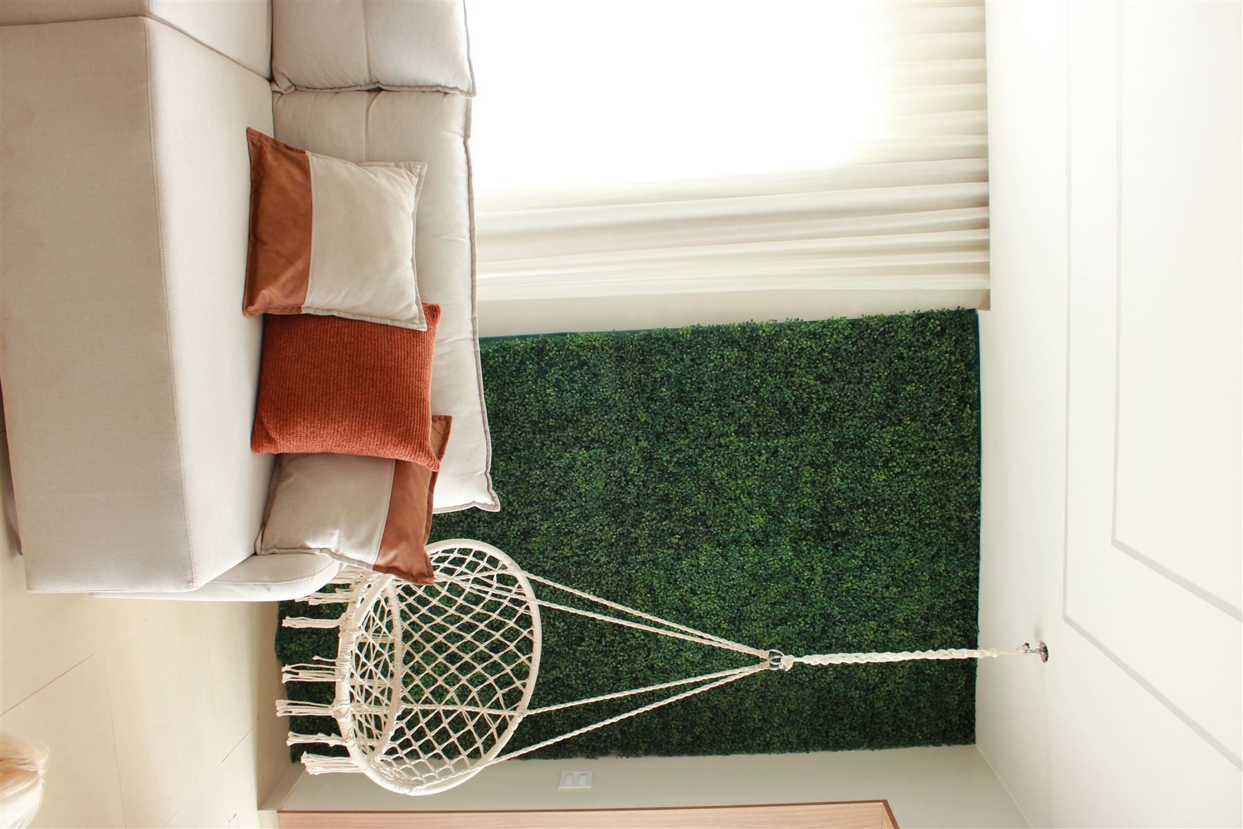 Sala de estar com parede de jardim vertical e cadeira suspensa